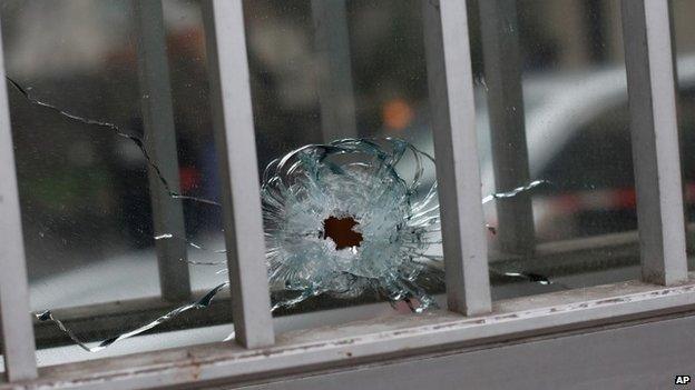 A bullet impact is seen in a window of a building next to the French satirical newspaper Charlie Hebdo"s office, in Paris, Wednesday, Jan. 7, 2015