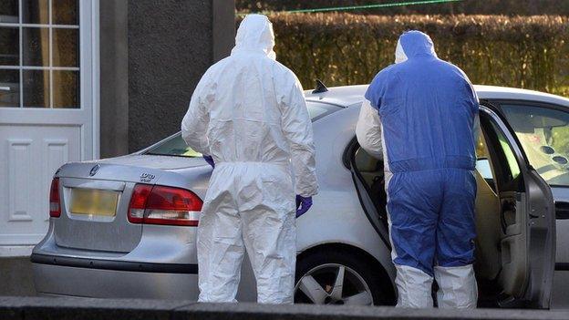 Forensic investigators examine a car at the scene of the murder