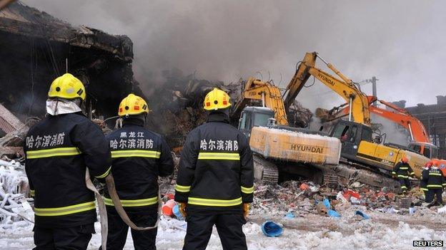 Firefighters look on as they search for missing firefighters at a building partially collapsed due to a fire, in Harbin, Heilongjiang province on 3 January, 2015