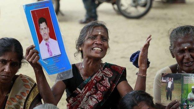 Sri Lankan ethnic Tamil women cry holding portraits of their missing relatives during a protest in Jaffna, Sri Lanka, Friday, Nov. 15, 2013