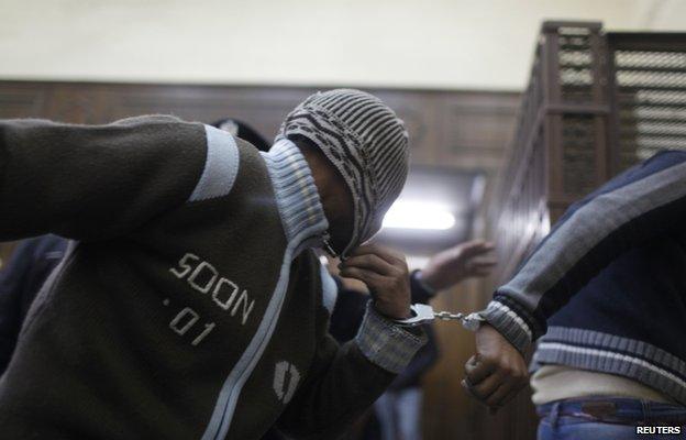 Defendants enter a cell a few minutes before they hear the verdict at a court in Cairo January 12, 2015