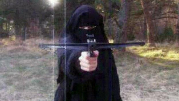 Hayat Boumeddiene points a crossbow at a camera