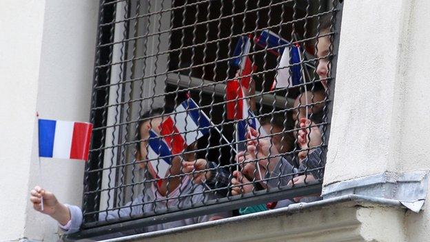 Children wave French flags from a school window