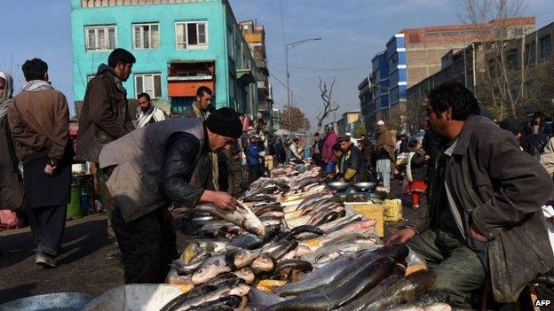 December 29, 2014, Afghan fishmongers prepares their fish for the customers at a roadside market in Kabul
