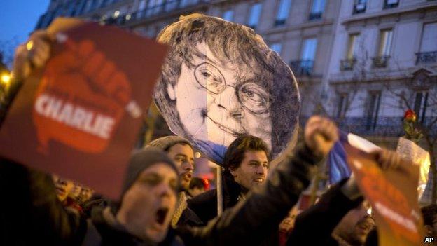 People demonstrate on Republique square with a portrait of slain Charlie Hebdo cartoonist Jean Cabut known as Cabu, during the demonstration in Paris, France, Sunday, Jan. 11, 2015.