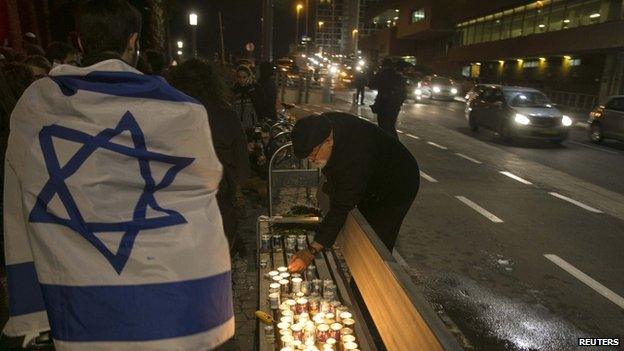 People light candles in front of the French embassy in Tel Aviv