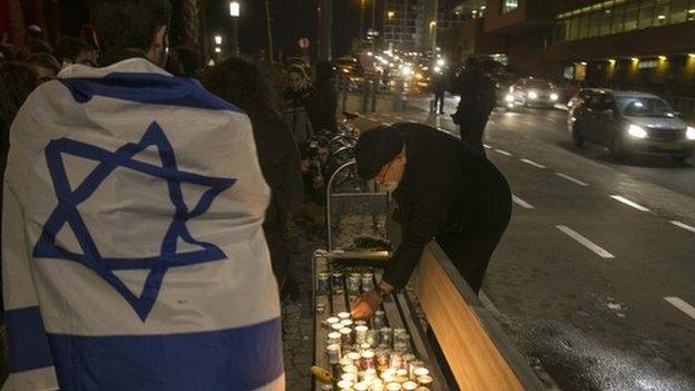 People light candles in front of the French embassy in Tel Aviv