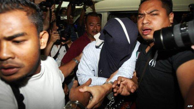 Malaysian security officers carry away one of the policemen (C) with covered face found guilty in a Mongolian model girl murder case, at Shah Alam high court outside Kuala Lumpur on 9 April 2009.