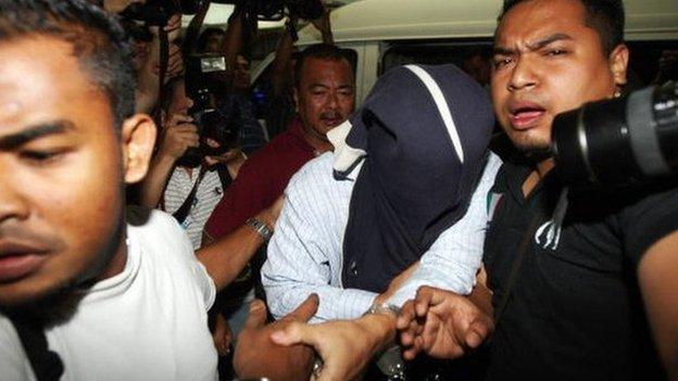 Malaysian security officers carry away one of the policemen (C) with covered face found guilty in a Mongolian model girl murder case, at Shah Alam high court outside Kuala Lumpur on 9 April 2009.