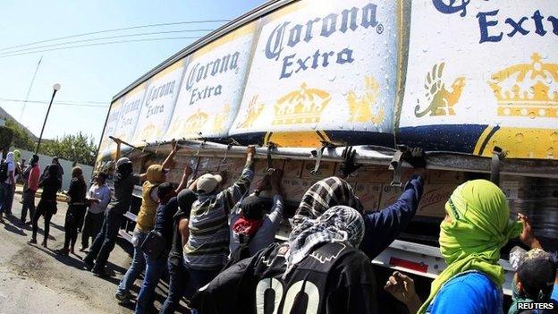 Activists take bottles from a beer truck to throw against the military police during a demonstration in the military zone of the 27th infantry battalion in Iguala on 12 January, 2015.