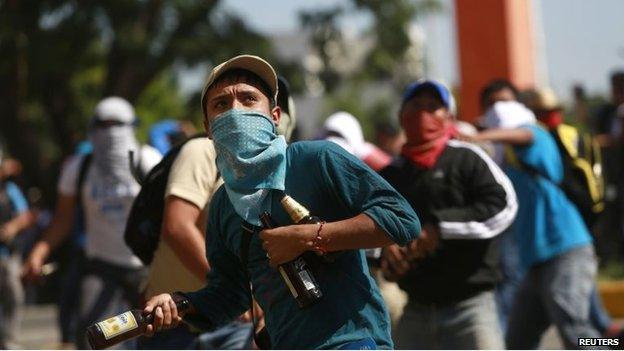 An activist throws bottles during a demonstration at the base of the 27th infantry battalion in Iguala on 12 January 2014