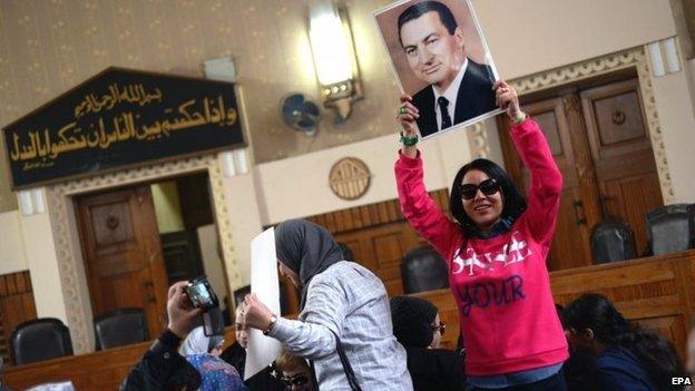 Supporter of Hosni Mubarak holds up a photo of the former Egyptian president after his conviction for embezzlement is overturned (13 January 2015)