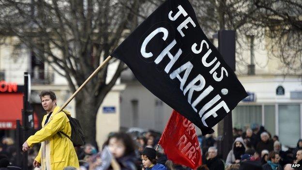 A man waves a flag reading 'Je suis Charlie' during a unity rally in Paris. Photo: 11 January 2015