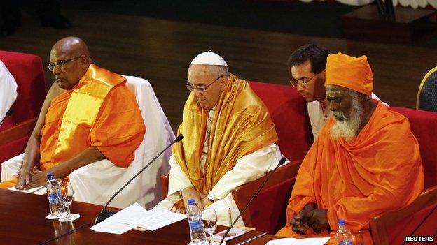 Pope Francis wears a saffron-coloured robe as he sits next to Hindu Nude-Kurukkal SivaSri T Mahadeva (R) and Buddhist monk Ittapane Dhammalankara (L) during the Interreligious Encounter at the Bmich in Colombo 13 January 2015