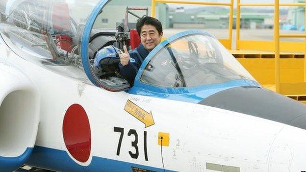 Japanese Prime Minister Shinzo Abe poses inside a T-4 training jet plane of the Air Self-Defense Force's Blue Impulse flight team at the ASDF base in Higashimatsushima, Miyagi prefecture on 12 May 2013.