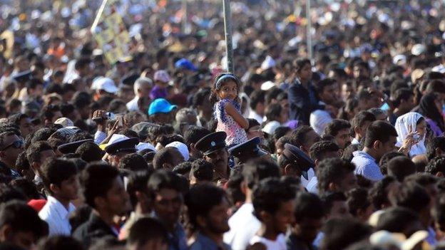 A Sri Lankan Catholic girl climbs a pole in the crowd during a canonisation mass for Joseph Vaz at Galle Face Green on January 14