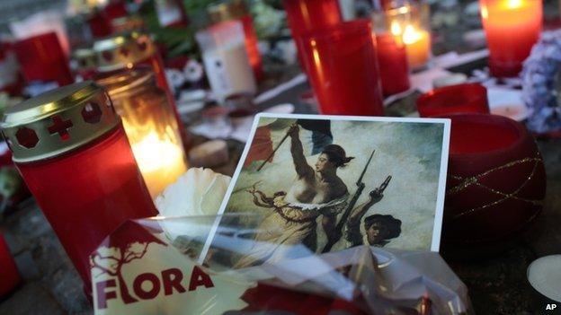 A painting of the "Marianne", the national symbol of the French Republic is placed between candles to commemorate the victims