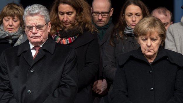 German President Joachim Gauck (L) and Chancellor Angela Merkel (R) attend a vigil for the victims of the attacks in France at the Brandenburg Gate in Berlin