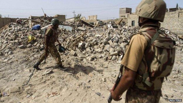 Pakistani soldiers stand near the debris of a house which was destroyed during a military operation against Taliban militants in the town of Miranshah in North Waziristan in this July 9, 2014