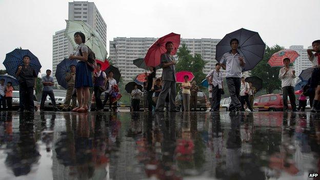 People standing with umbrellas in Pyongyang