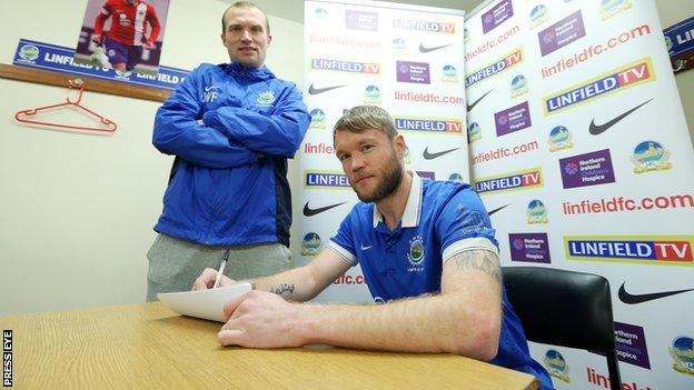 Grant McCann signs on the dotted line for Linfield with manager Warren Feeney looking on