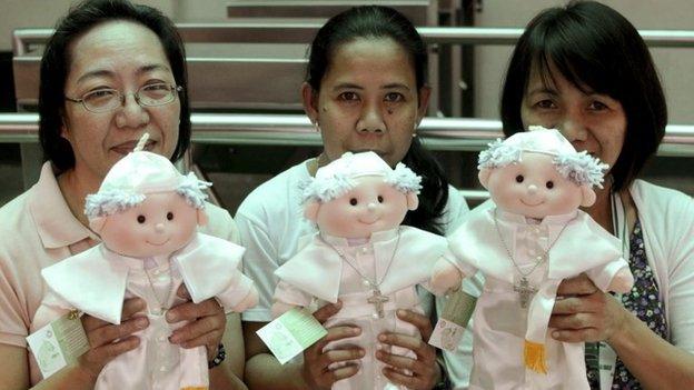 Filipino devotees hold limited edition Pope Francis dolls that are sold by the De La Salle University in Manila, Philippines Wednesday, Jan. 14, 2015.