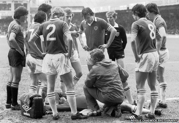 Players standing over goalkeeper Mark Wallington