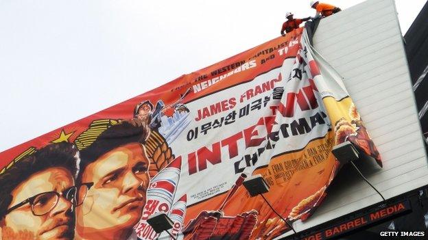 Workers remove the poster for The Interview from a billboard in Hollywood, California 18 December 2014