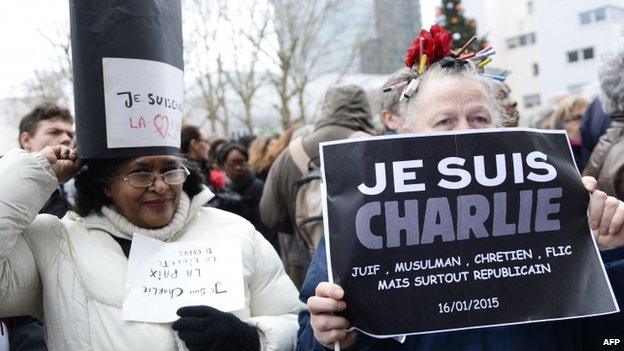 Women hold placards saying Je Suis Charlie at Tignous's funeral