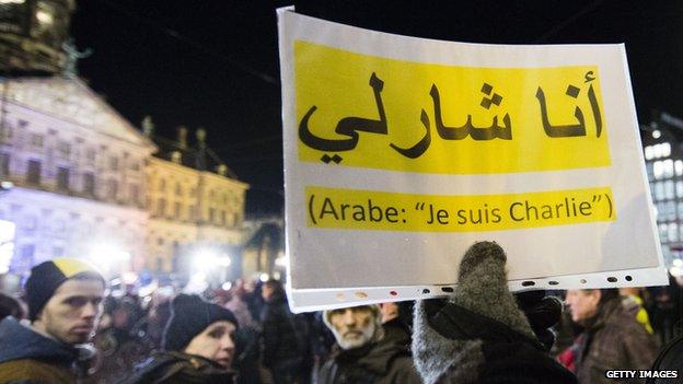 People hold up "Je Suis Charlie" placard in Arabic