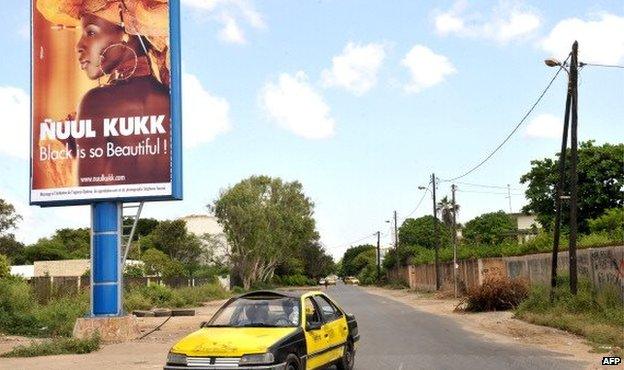 A taxi passes by a Nuul Kukk ('All Black') citizen's movement poster which reads 'Black is so Beautiful!' - October 2012 in Dakar, Senegal