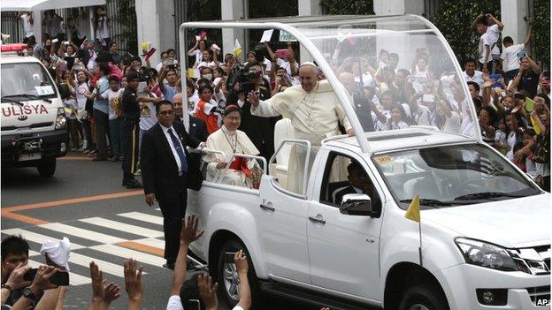 Pope Francis waves to the faithful from his Popemobile as his motorcade leaves the Presidential Palace for the Manila Cathedral Friday, 16 January 2015 in Manila, Philippines.