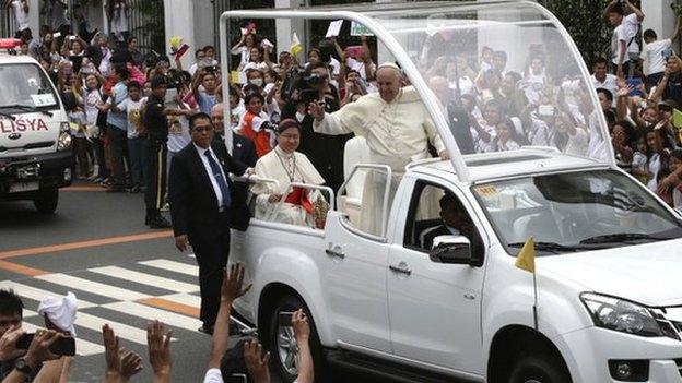 Pope Francis waves to the faithful from his Popemobile as his motorcade leaves the Presidential Palace for the Manila Cathedral Friday, 16 January 2015 in Manila, Philippines.