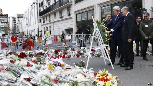 US Secretary of State John Kerry (C) and French Foreign Affairs minister Laurent Fabius lay a wreath of flower to pay tribute to the victims killed in the attack of the satirical newspaper Charlie Hebdo