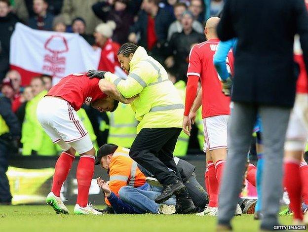 A man is tackled by stewards after the final whistle