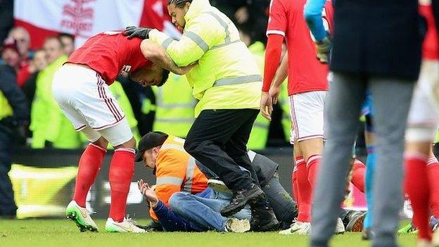 A man is tackled by stewards after the final whistle