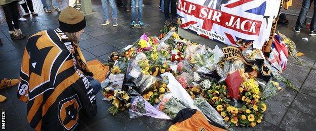 A Wolves fan lays a tribute to Sir Jack Hayward outside Molineux Stadium ahead of kick-off