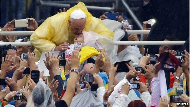 Pope Francis kisses a child as he arrives to lead an open-air Mass at Rizal Park