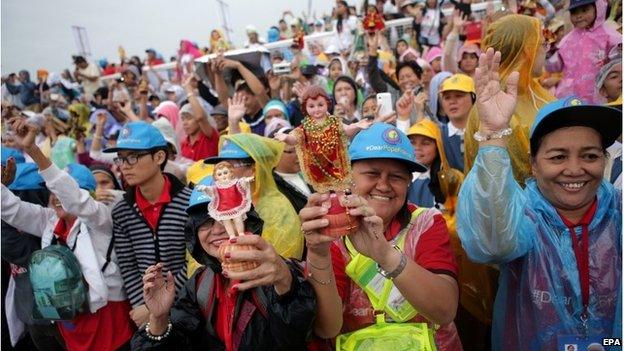 Filipino devotees hold up their "Child Jesus" statues.