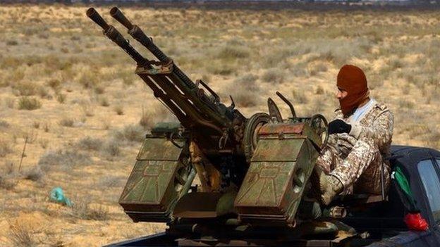 A fighter from the Fajr Libya (Libya Dawn) militia sits on a pick up truck mounted with a machine gun during clashes with forces loyal to Libya