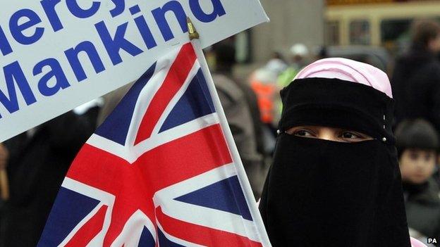 A Muslim woman waves a British flag at a rally