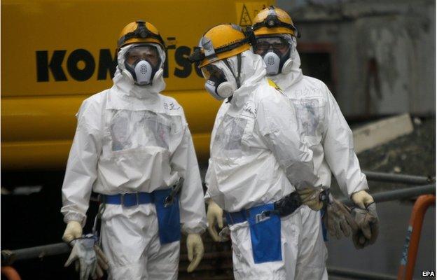 Workers prepare themselves prior to operate in front of Unit Three under the decommissioning of its reactors at tsunami-crippled Tokyo Electric Power Co.'s Fukushima Daiichi Nuclear Power Plant in Okuma, Fukushima Prefecture, northern Japan, 11 December 2014