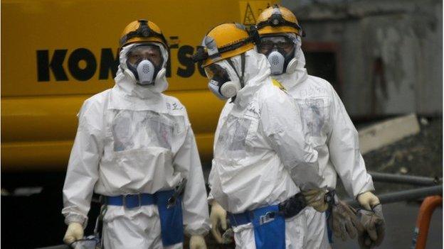 Workers prepare themselves prior to operate in front of Unit Three under the decommissioning of its reactors at tsunami-crippled Tokyo Electric Power Co.'s Fukushima Daiichi Nuclear Power Plant in Okuma, Fukushima Prefecture, northern Japan, 11 December 2014