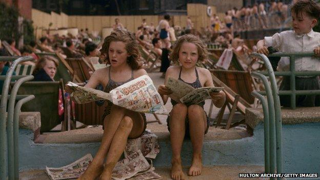 Two children read a newspaper in 1956