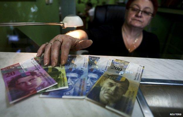 Cashier at currency exchange office in Warsaw with Swiss Francs