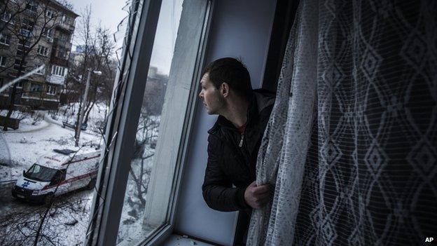 A man looks out of his damaged window in Donetsk (18 Jan)