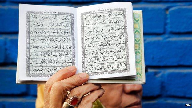 Woman holds up a copy of the Koran in protest