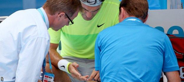 Roger Federer inspects his hand in his match against Simone Bolelli