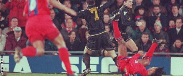 Eric Cantona holds his arms aloft as Crystal Place defender Richard Shaw falls to the ground