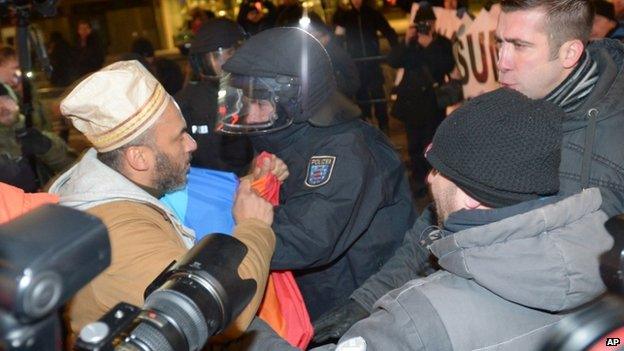 A police officer separates an anti-Pegida protester (left) and Pegida supporters in Leipzig